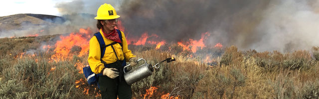 Crew member in front of burning wild fire