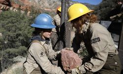 Two crew members pass off a large rock in desert canyon